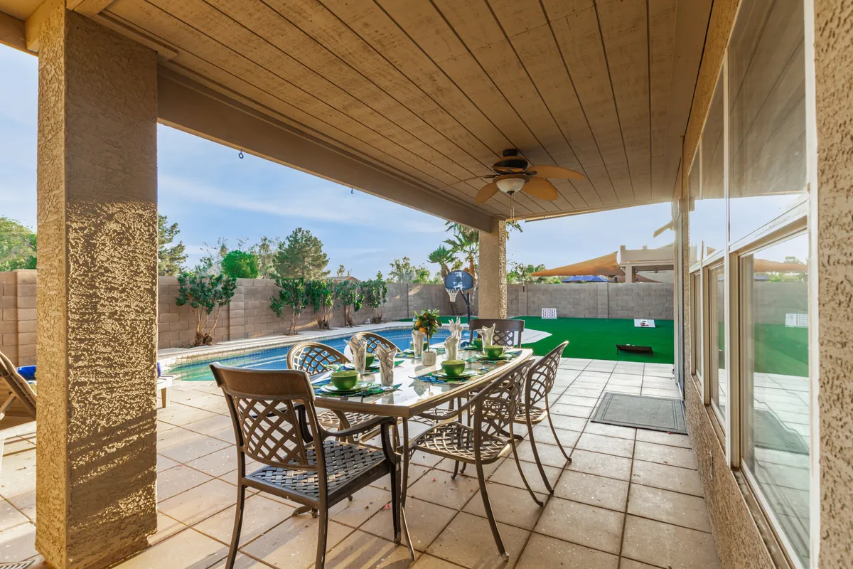 A relaxed exterior image featuring a poolside dining table set within a landscaped yard. The setting suggests relaxation, celebration, and easy transition between home comforts and community events—mirroring the ease of accessing the Heritage District from home.