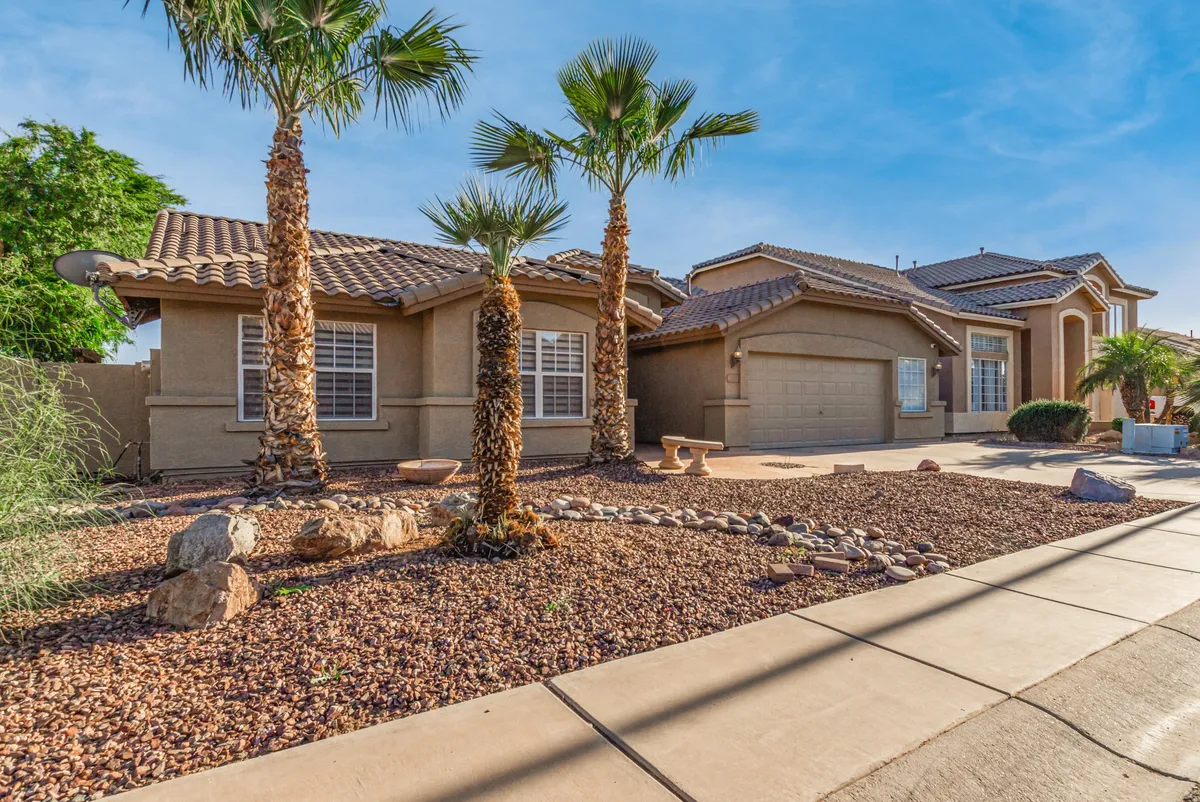 This exterior image showcases the inviting facade of the house surrounded by palm trees and rock landscaping. The warm, natural lighting hints at a peaceful outdoor environment, making it ideal for morning coffee or a midday study break.