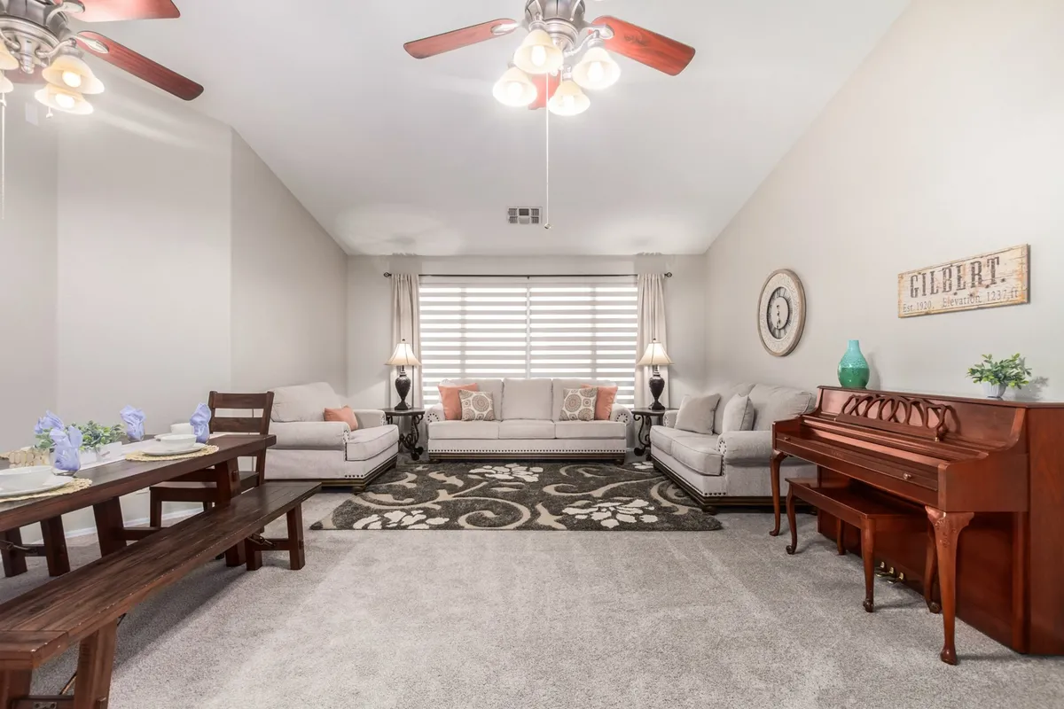 This view includes sofa seating, a wooden dining table, a prominently displayed piano, and decorative wall art. The setup is inviting and demonstrates multiple opportunities for family gatherings, music, and relaxed conversation.